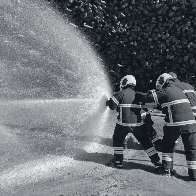 Simulacro de emergencia: dos brigadistas operando una línea de agua.