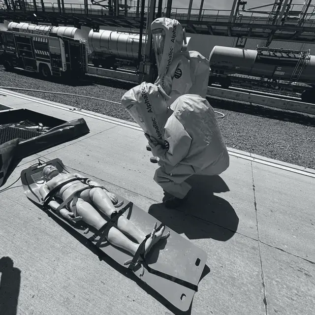 Simulacro de rescate con traje de protección química y camilla de evacuación.